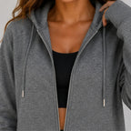 Close-up of women's gray zip-up hooded jacket zipper, hood, and fabric