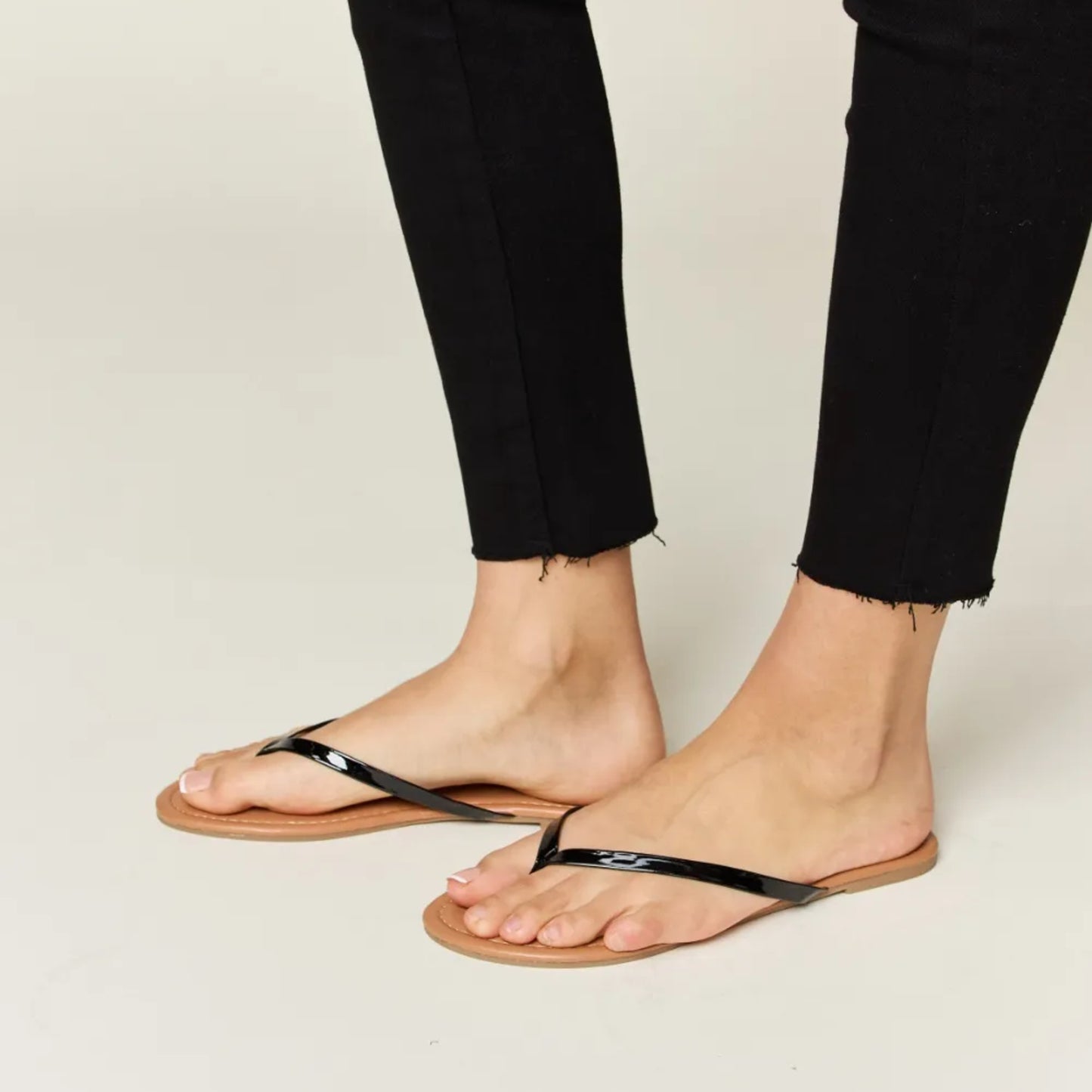 Person wearing black sandals with a neutral background