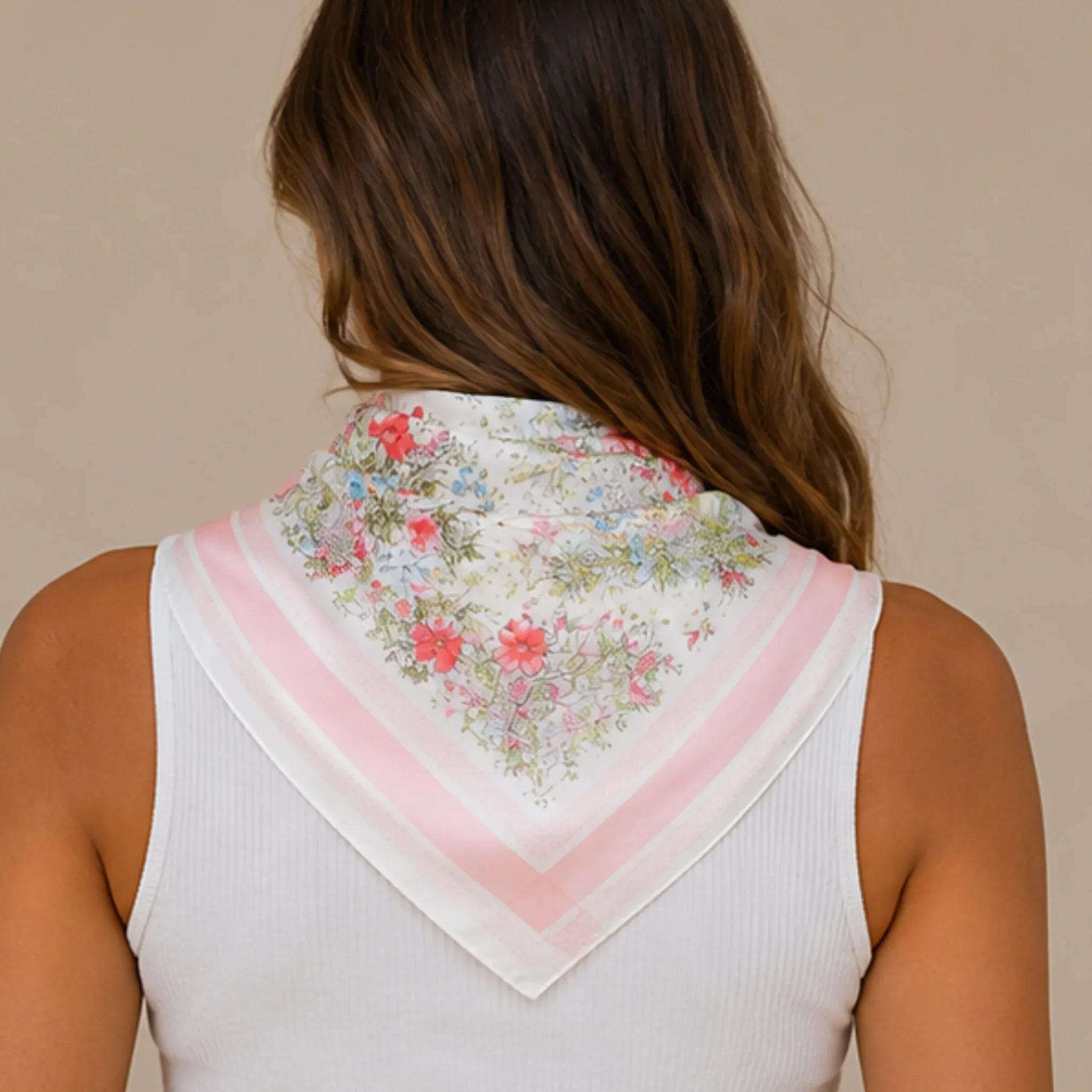 Back view of a pink floral multi print square scarf draped over the shoulders showcasing the floral print and soft pink border.