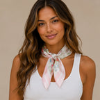 Woman wearing a pink floral multi print square scarf tied around the neck with a soft feminine floral design.