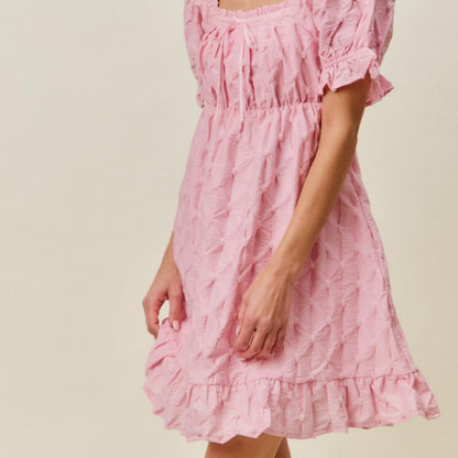 Side profile of the SO ME pink texture woven mini dress highlighting the ruffled hem.