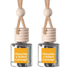 Two matching car air fresheners with clear glass bottles, beige wooden diffusers, and orange labels reading 'Pistachio & Salted Caramel', shown on a white background.