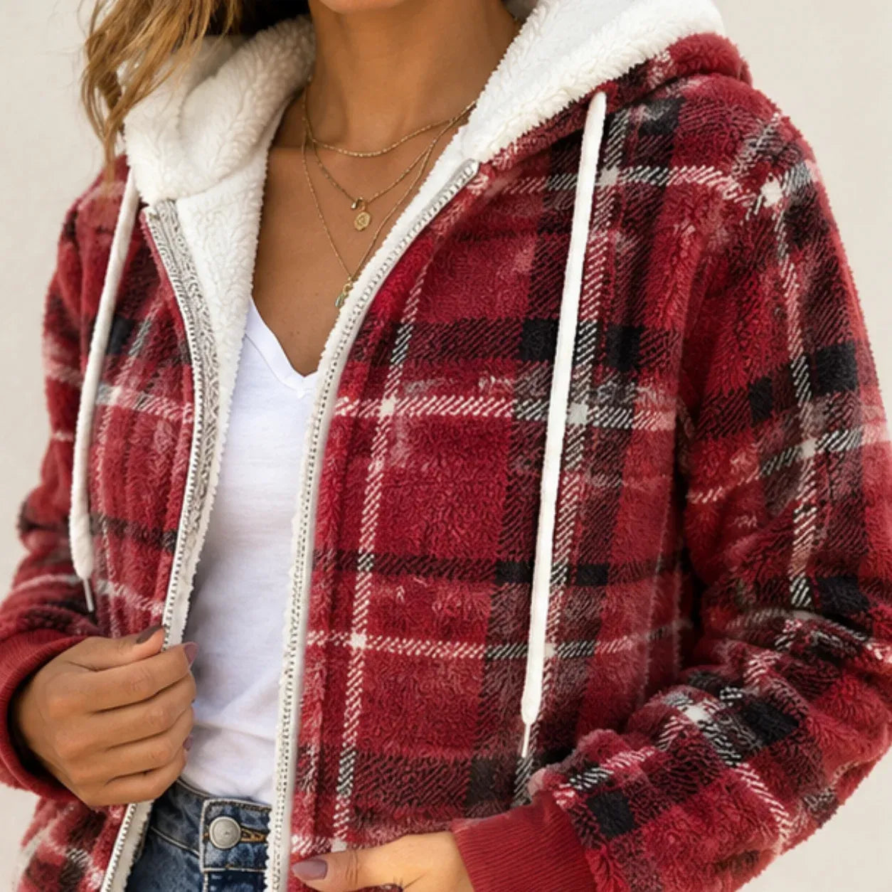 Close-up of women's red plaid fleece-lined hooded zip-up jacket showing sherpa lining, zipper, and plaid texture
