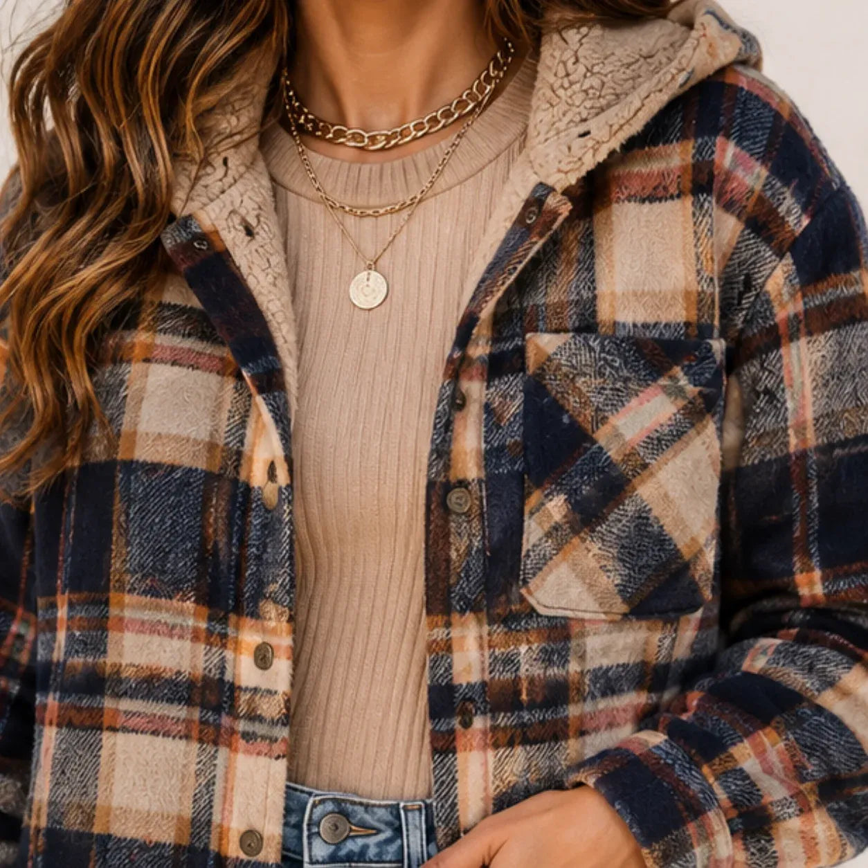 Close-up of the plaid fabric, sherpa hood lining, buttons, and chest pocket on a brown hooded shacket