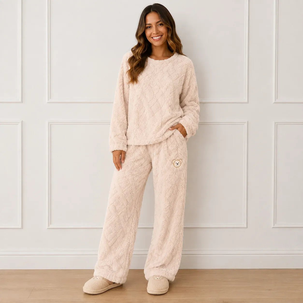 Woman wearing a cozy beige plush fleece pajama set with long sleeves, wide-leg pants, and bear detail