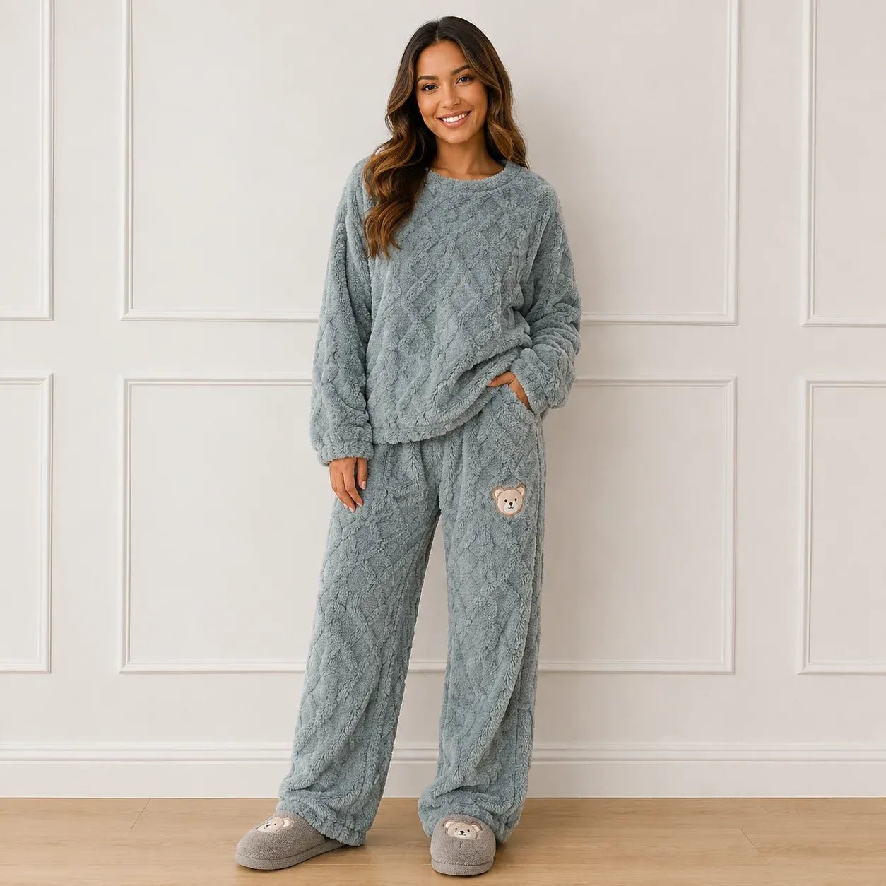 Woman wearing a cozy blue plush fleece pajama set with long sleeves, wide-leg pants, and bear detail