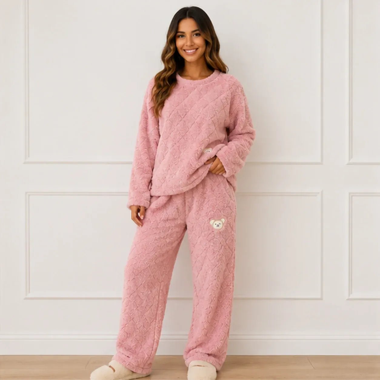 Woman wearing a pink plush fleece pajama set with long sleeves, wide-leg pants, and bear detail
