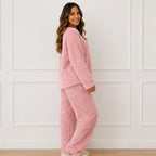 Side view of woman wearing a pink plush fleece pajama set with long sleeves and wide-leg pants