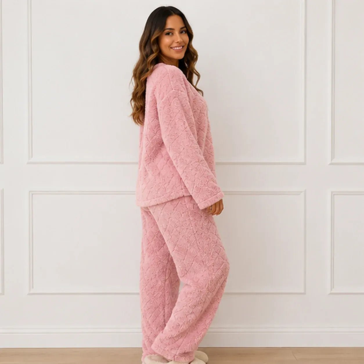 Side view of woman wearing a pink plush fleece pajama set with long sleeves and wide-leg pants
