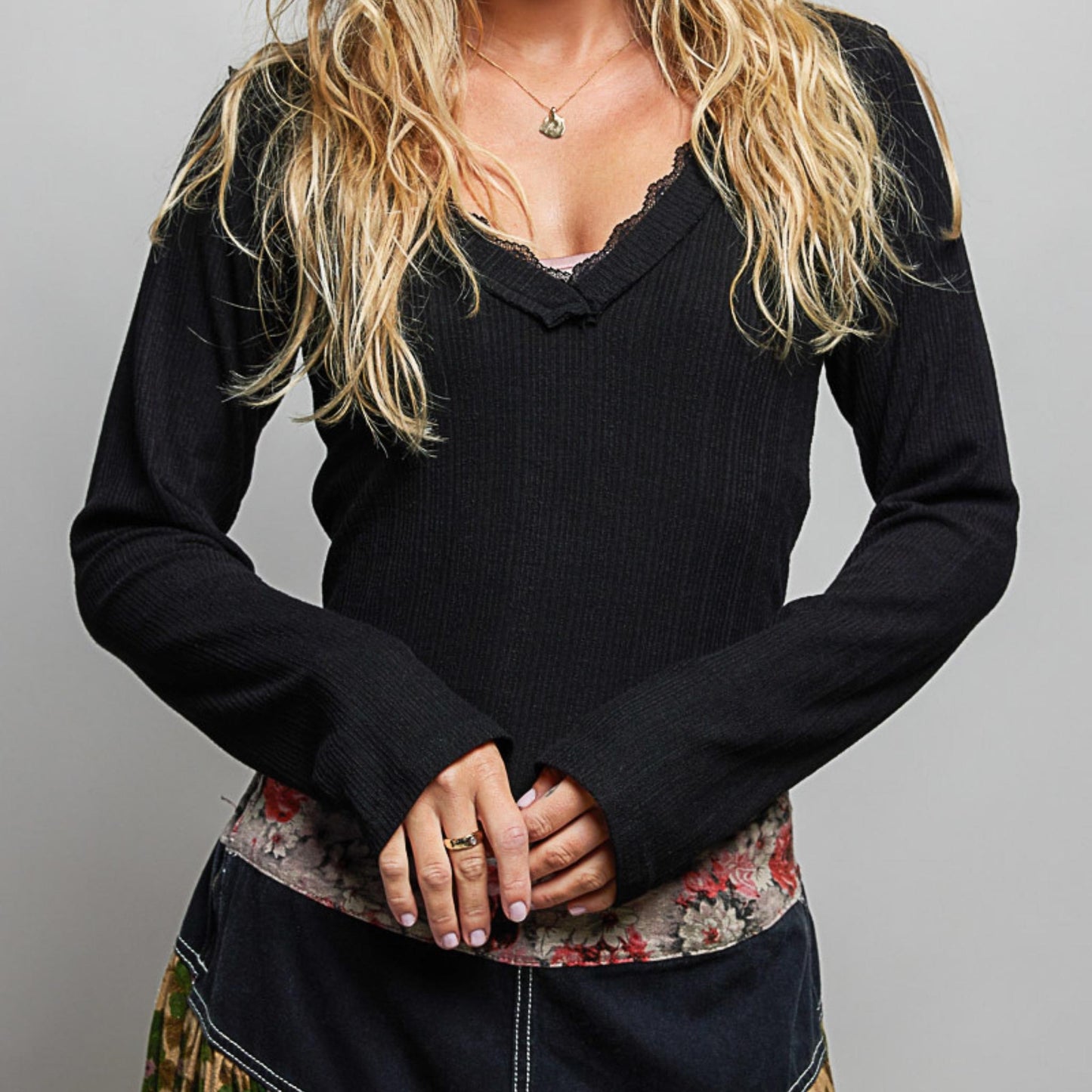 POL black v-neck long sleeve ribbed top styled with floral skirt — front view.