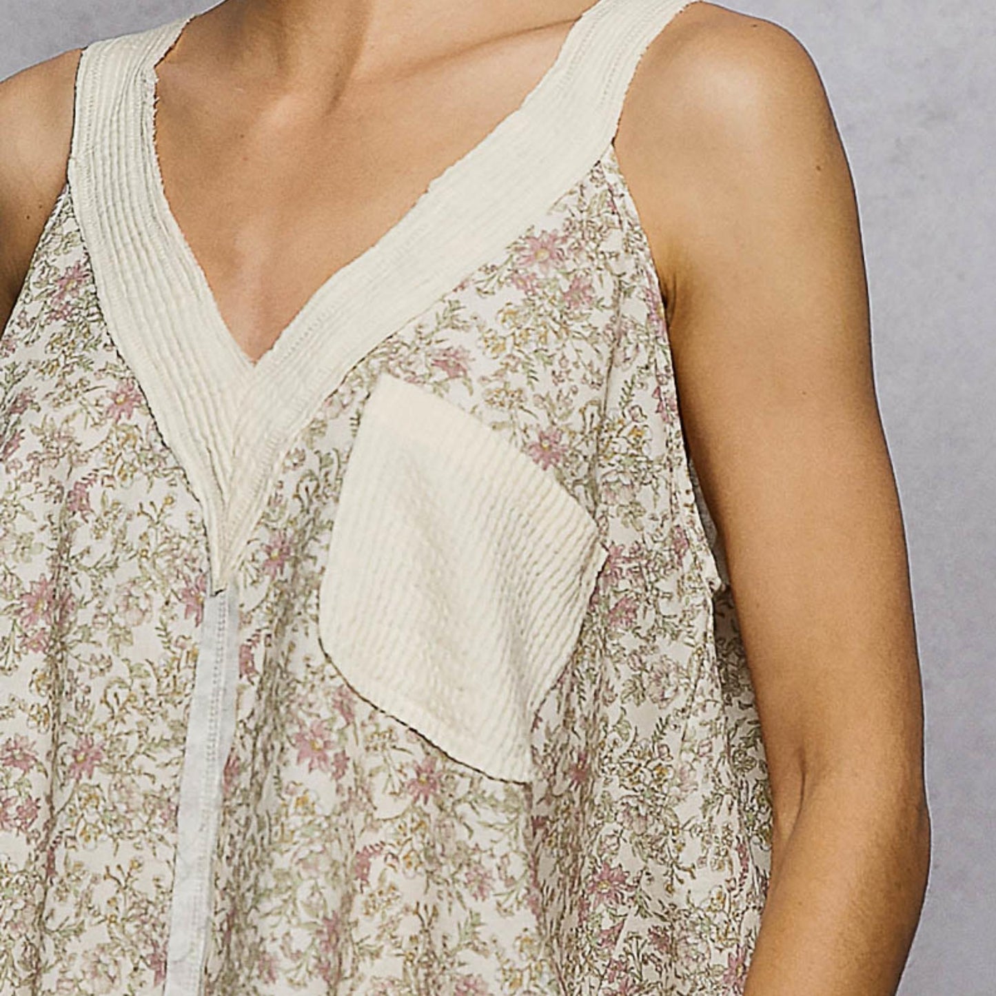 Close-up detail of the functional front pocket and V-neckline on the floral tank.