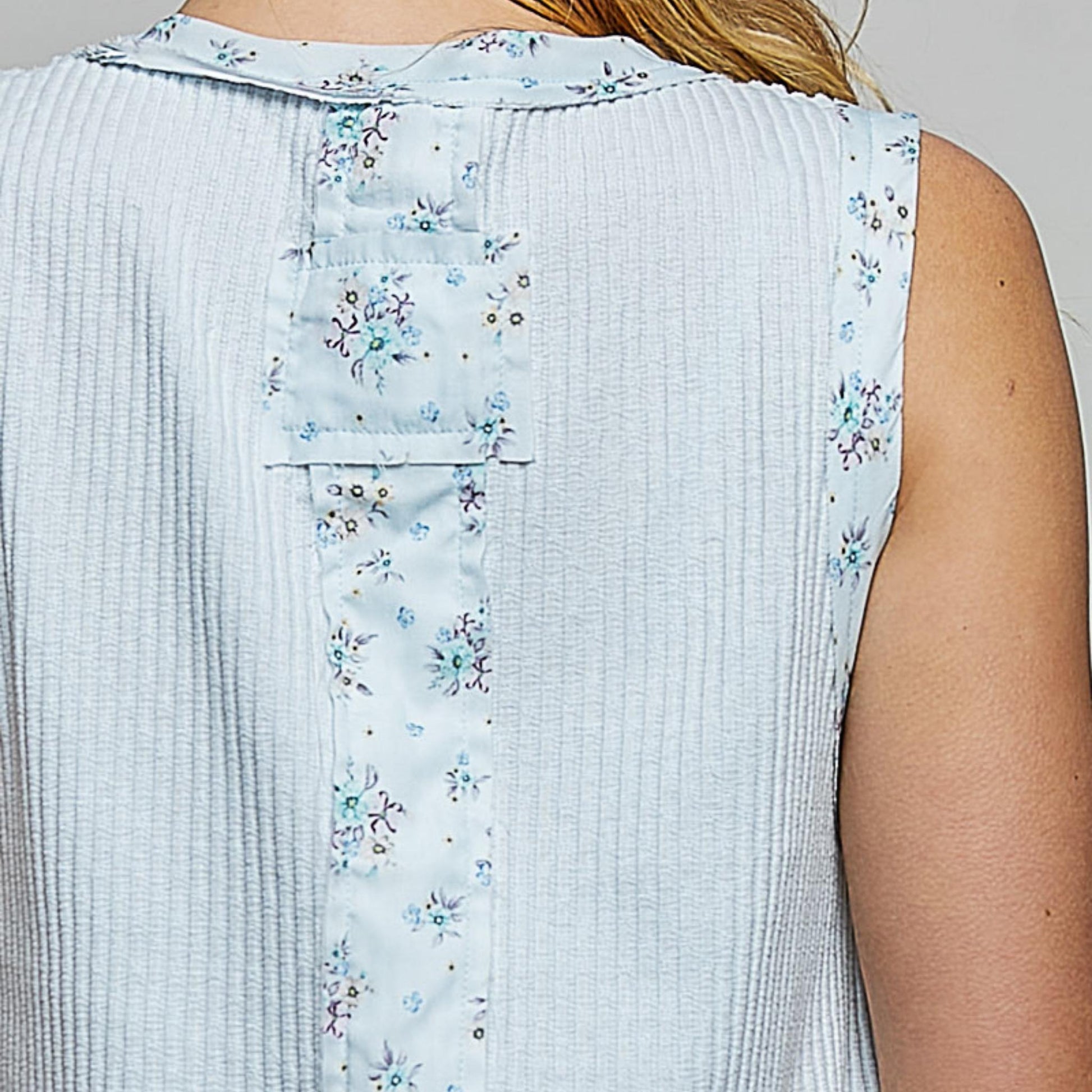 Light blue sleeveless top with floral pattern on a plain background