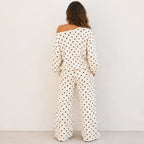 Back view of a woman wearing a white polka dot off-the-shoulder top and wide-leg pants set