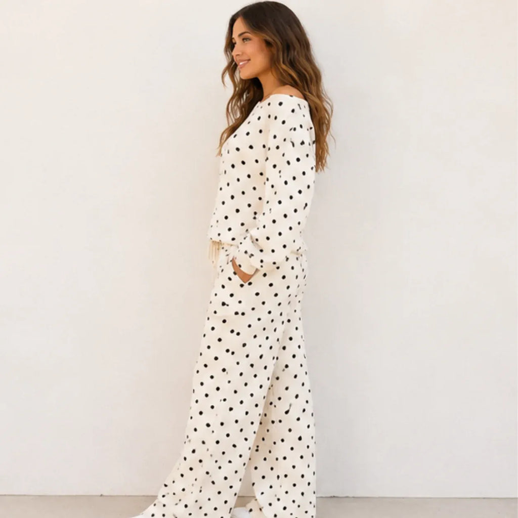 Side view of a woman wearing a white polka dot off-the-shoulder top and wide-leg pants set