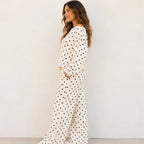 Side view of a woman wearing a white polka dot off-the-shoulder top and wide-leg pants set