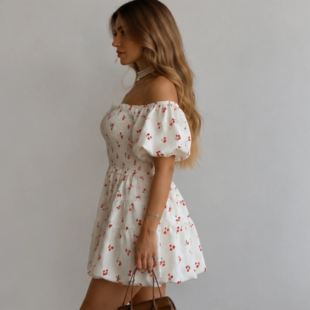 Women's Puff Sleeve Cherry Print Smocked Mini Dress side view featuring puff sleeves, an elastic smocked bodice, tiered mini skirt, and a feminine cherry print design.
