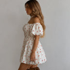 Women's Puff Sleeve Cherry Print Smocked Mini Dress side view featuring puff sleeves, an elastic smocked bodice, tiered mini skirt, and a feminine cherry print design.