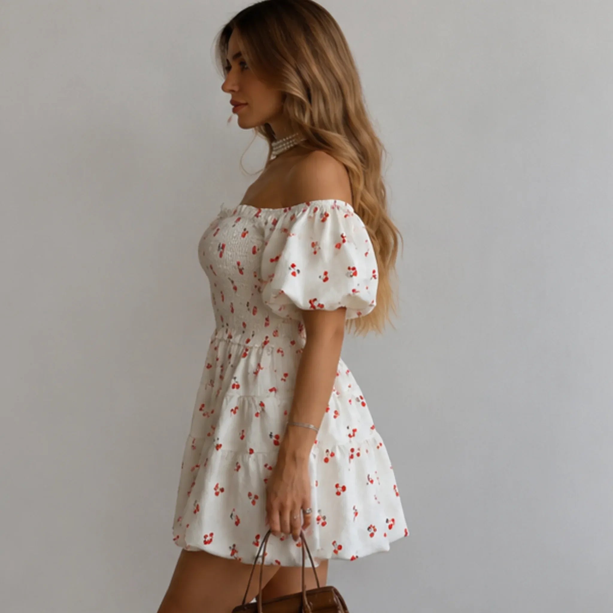 Women's Puff Sleeve Cherry Print Smocked Mini Dress side view featuring puff sleeves, an elastic smocked bodice, tiered mini skirt, and a feminine cherry print design.