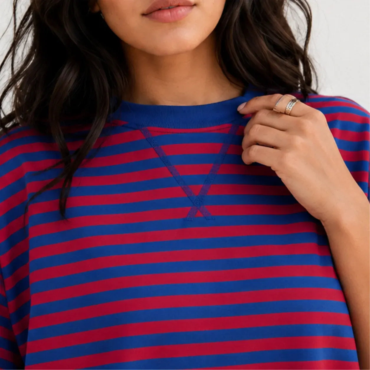 Close-up view of crew neckline with cross-stitch notch detail on red and royal blue striped lounge top