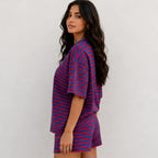 Side profile view of woman wearing red and royal blue horizontal striped short-sleeve top and shorts lounge set