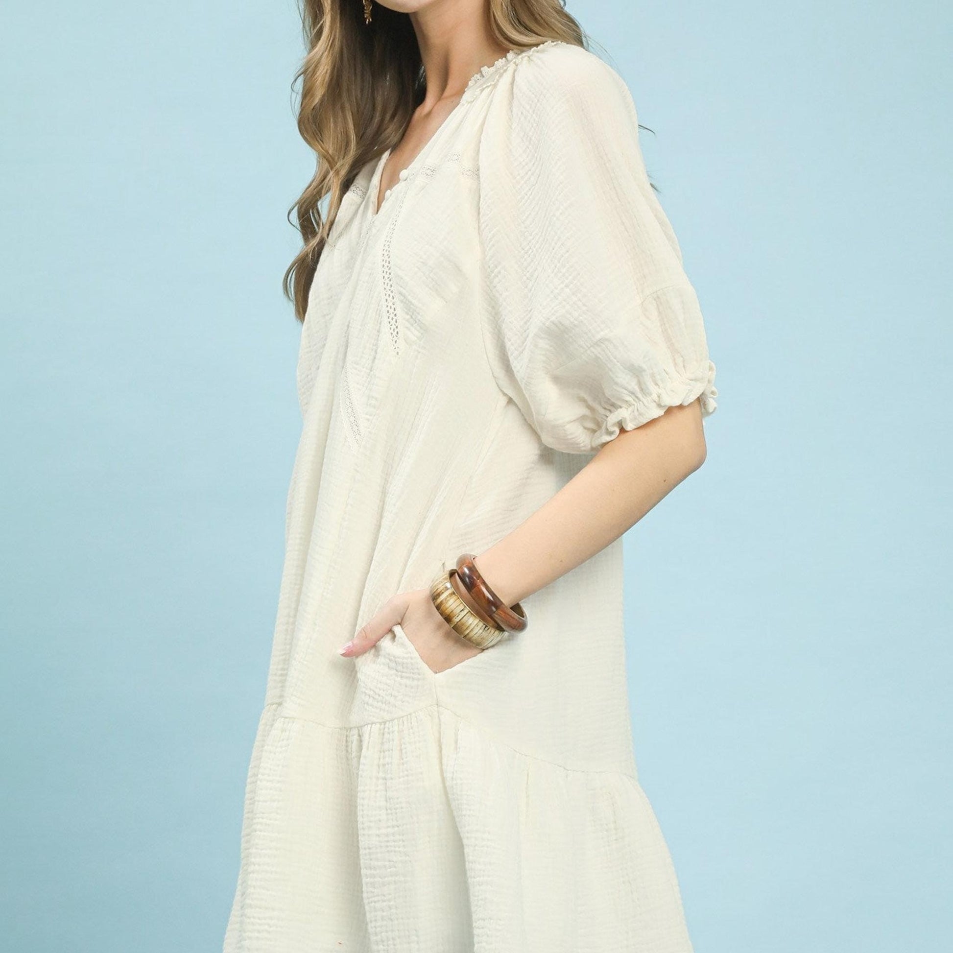 Woman wearing a white dress with puff sleeves against a light blue background