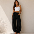Women's relaxed wide leg cotton pants in black featuring a loose fit, elastic waistband, and full-length design.