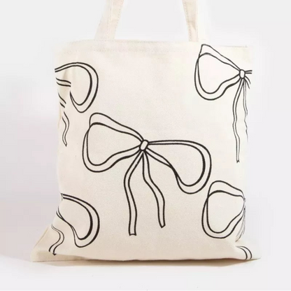 Ribbon bow tie print tote bag in black with white feminine bow patterns and shoulder straps