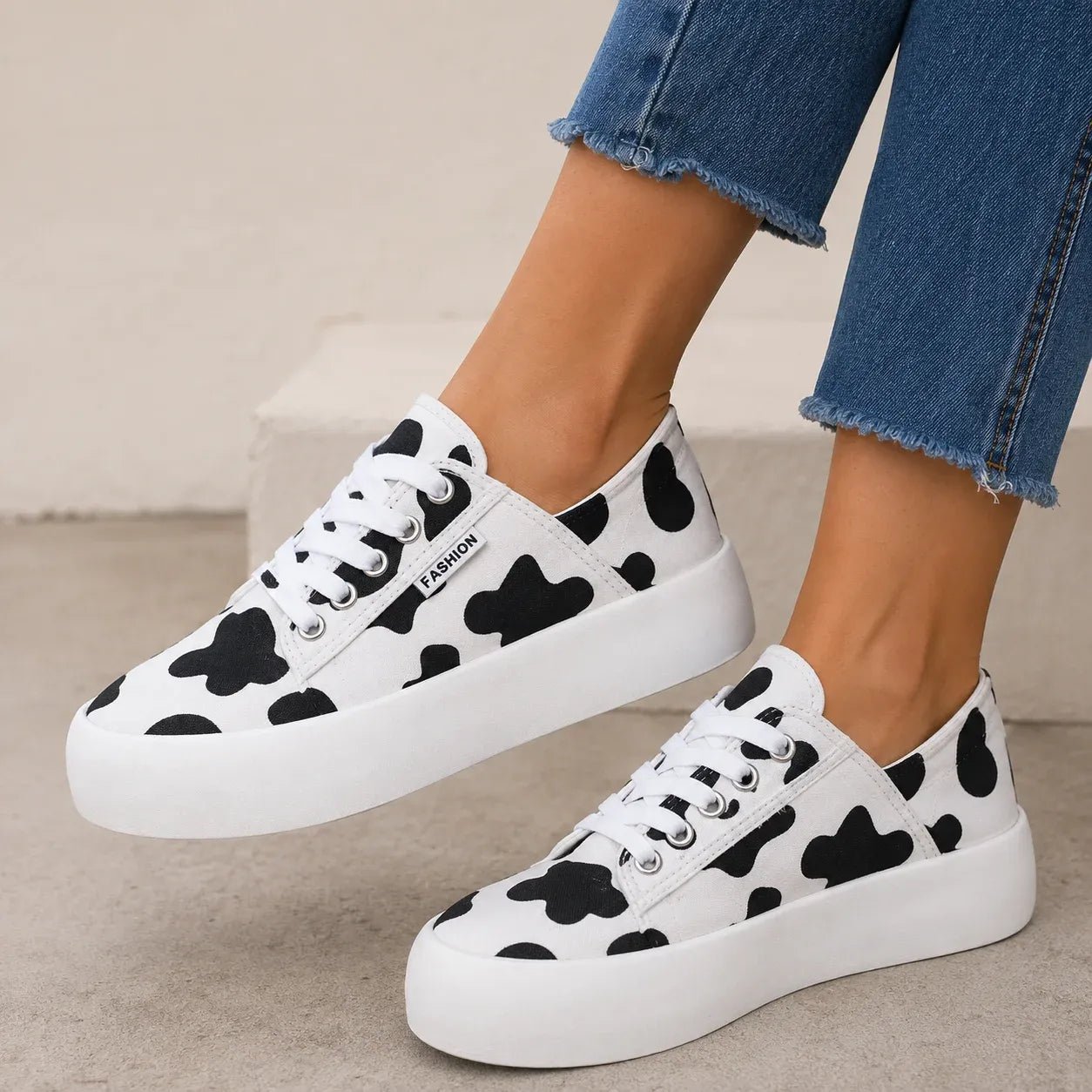 Cow print Roam Wild Convertible Sneakers with white platform soles and lace-up styling.