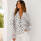 Women's white and black polka dot ruffle chiffon long sleeve blouse featuring cascading front ruffles, sheer sleeves, and a chic V-neck design.