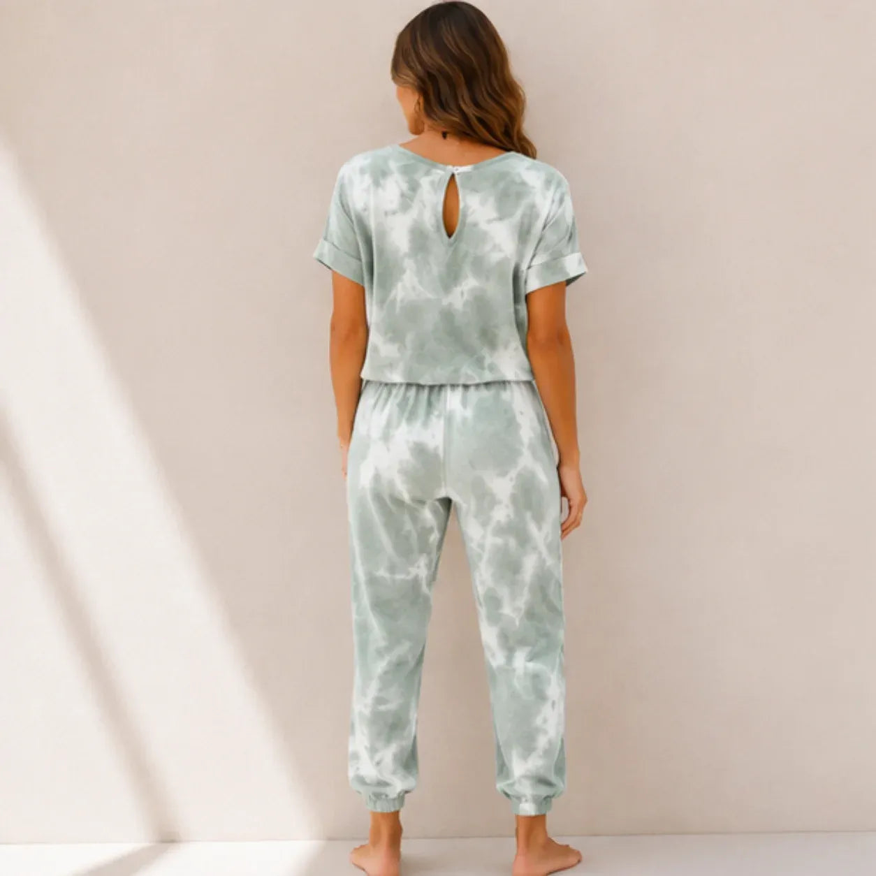 Back view of a women's sage green tie-dye matching loungewear set with short sleeve top and jogger pants.