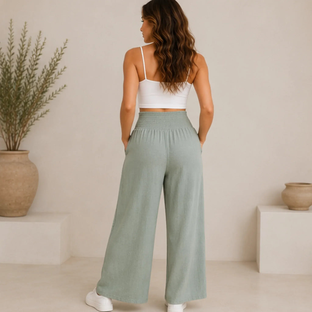 Back view of a woman wearing sage lightweight high-waisted wide-leg lounge pants featuring a comfortable smocked waistband.