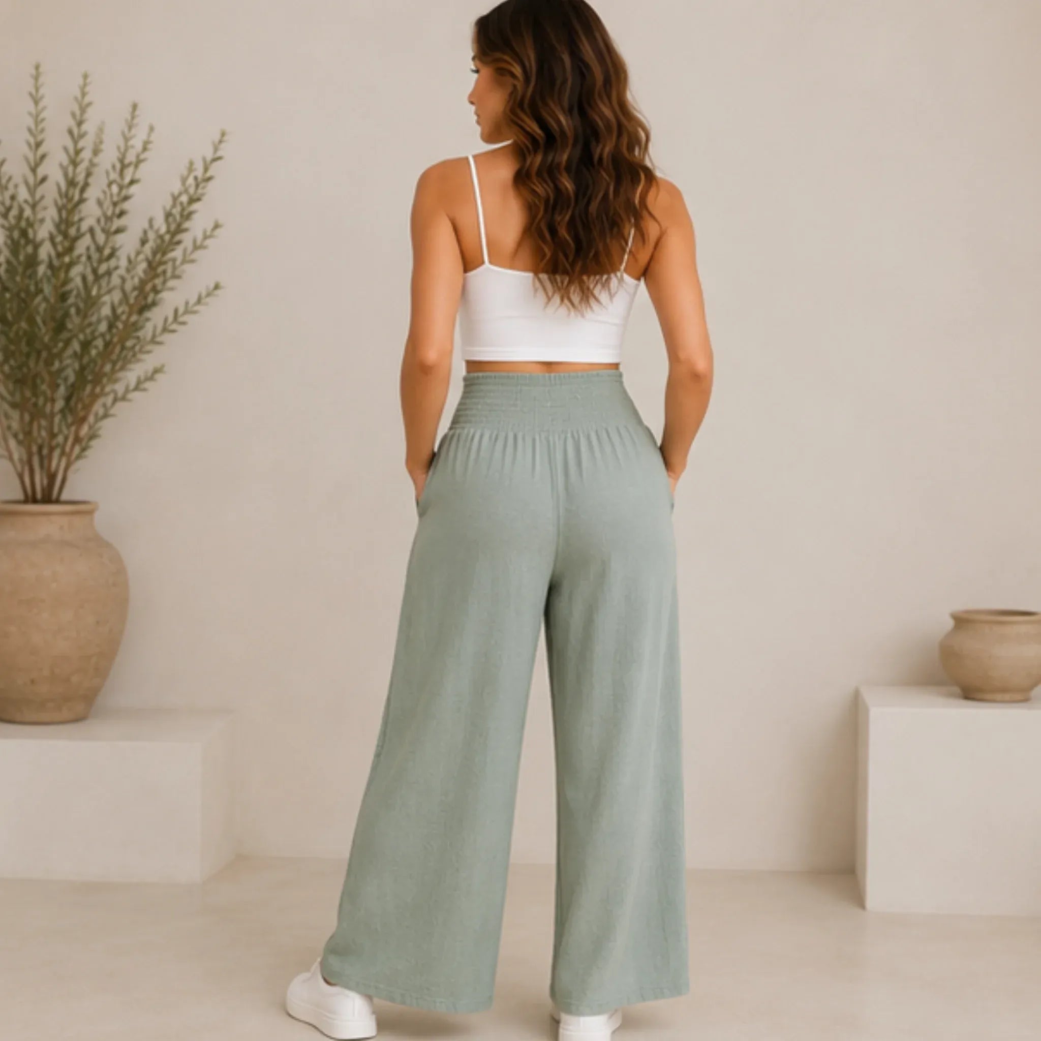 Back view of a woman wearing sage lightweight high-waisted wide-leg lounge pants featuring a comfortable smocked waistband.