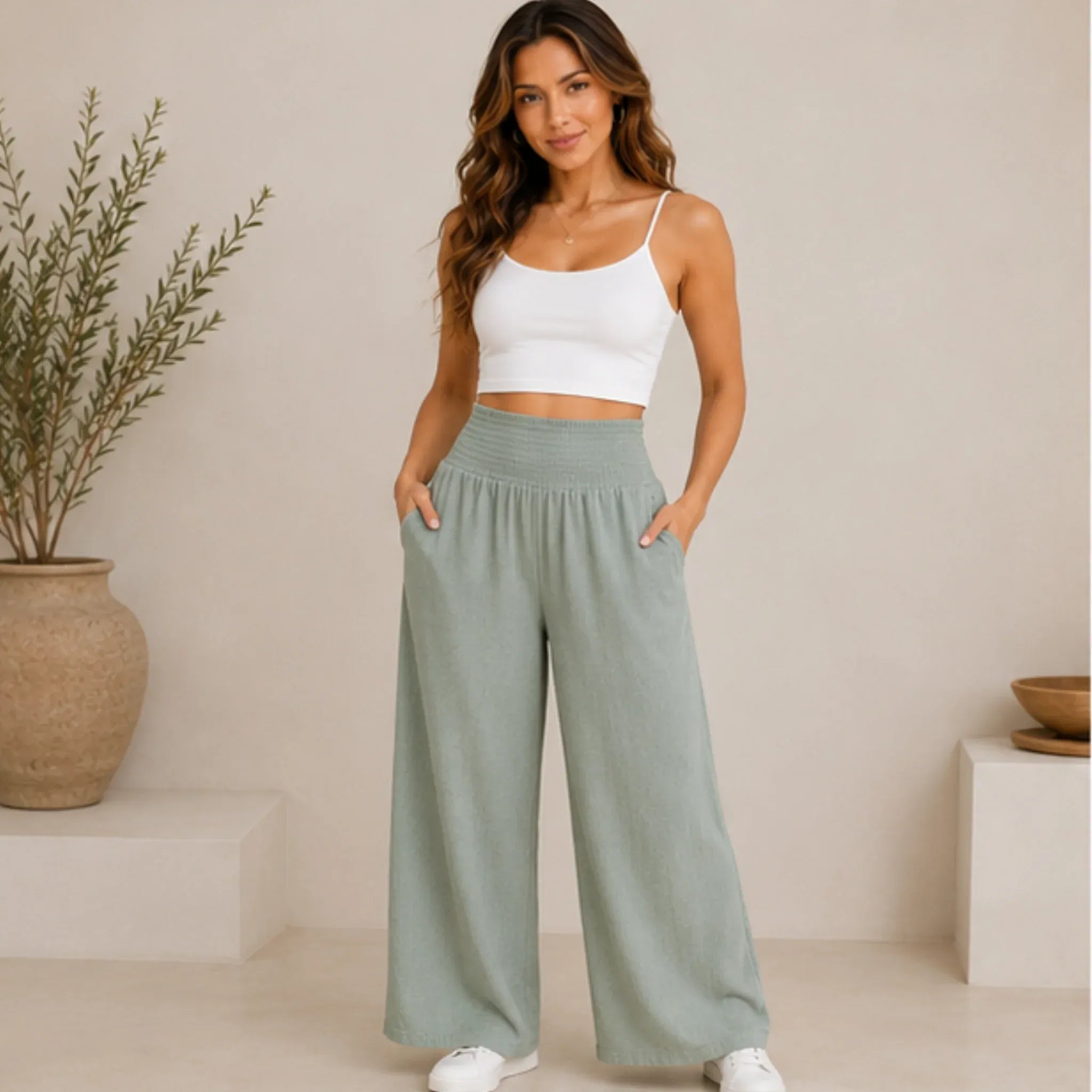 Woman wearing sage lightweight high-waisted wide-leg lounge pants with a smocked waistband and side pockets, front view.