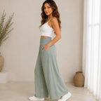 Side view of a woman wearing sage lightweight high-waisted wide-leg lounge pants with a relaxed fit and side pockets.