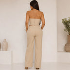 Back view of the Women's Sculpted Grace taupe two-piece set with a strapless zip-back peplum top and matching wide-leg pants.