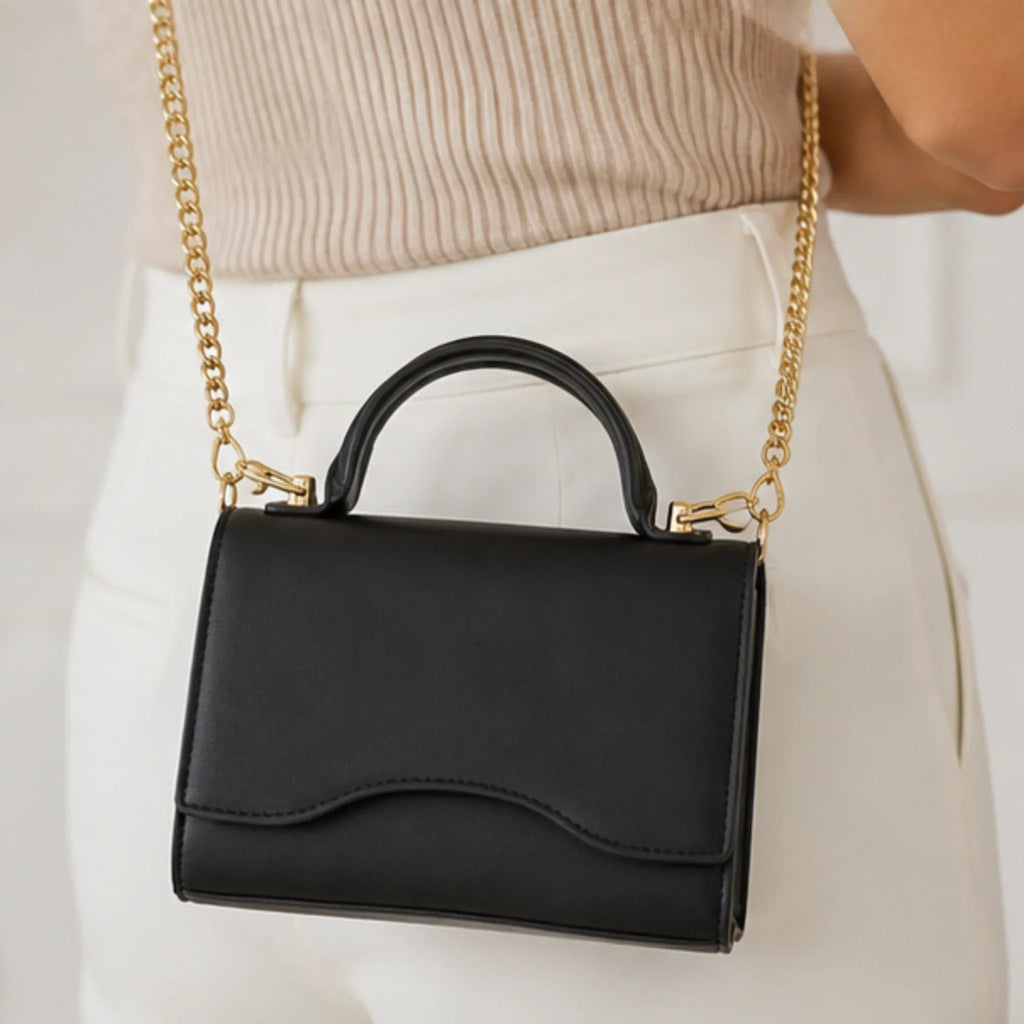 Close-up of the black Shiny Chain Crossbody Bag featuring a gold chain strap and top handle.