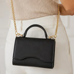 Close-up of the black Shiny Chain Crossbody Bag featuring a gold chain strap and top handle.