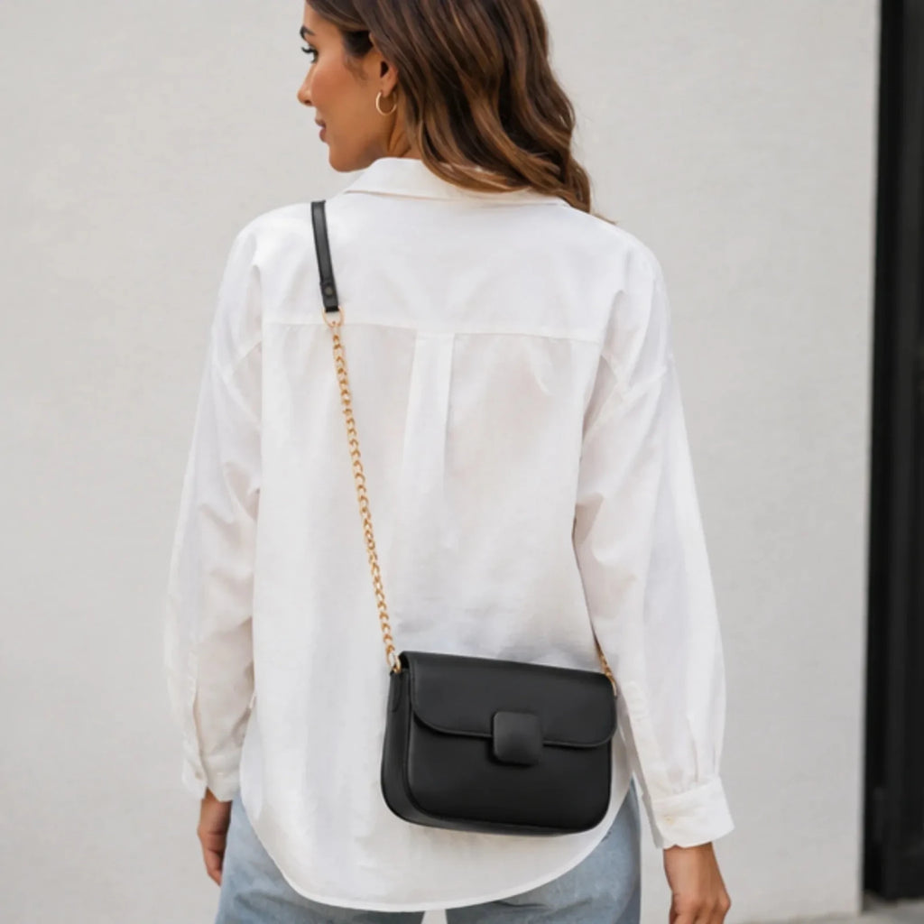 Back view of the black faux leather shoulder bag featuring a sleek structured design and gold chain shoulder strap.