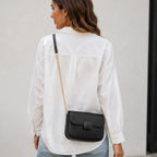 Back view of the black faux leather shoulder bag featuring a sleek structured design and gold chain shoulder strap.