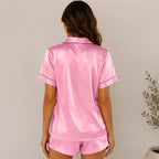 Back view of women's dark pink silky satin pajama shorts set with short sleeves and matching lounge shorts.