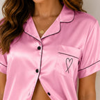 Close-up of women's dark pink silky satin button-up pajama shirt featuring lapel collar, pocket detail, and satin fabric.