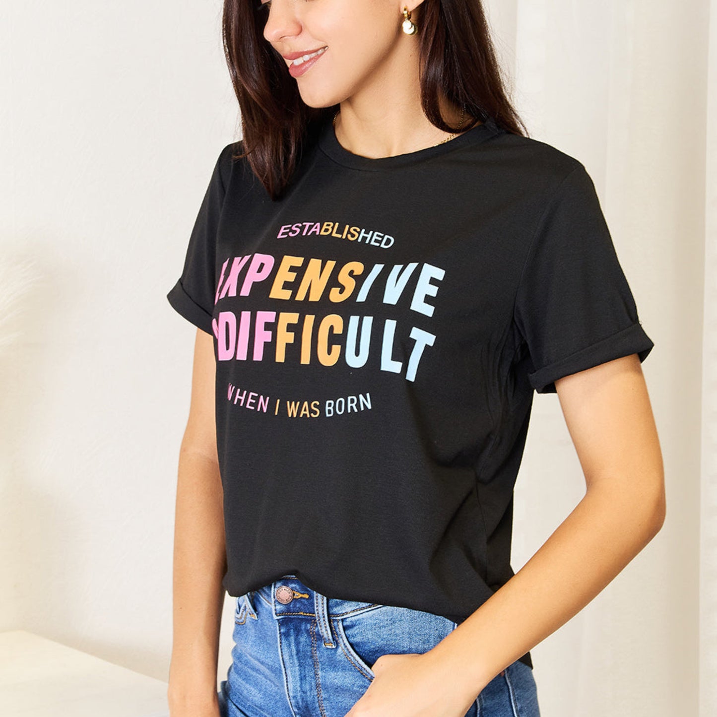 Woman wearing a black slogan graphic tee tucked into blue jeans.