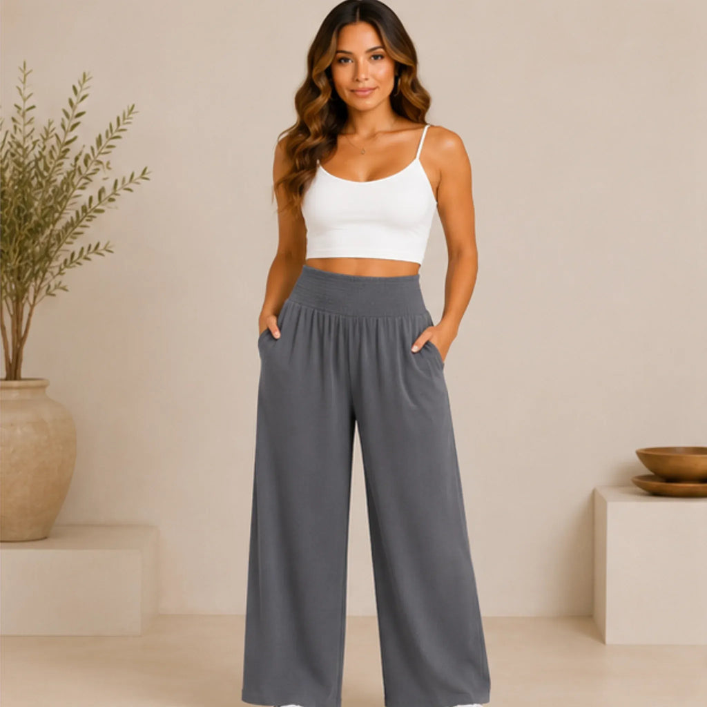 Woman wearing slate blue grey lightweight high-waisted wide-leg lounge pants with a smocked waistband and side pockets, front view.