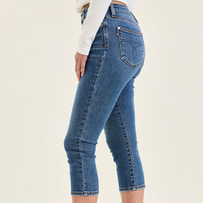 Close-up of the clean hem and slim leg opening on medium wash stretch denim capris.