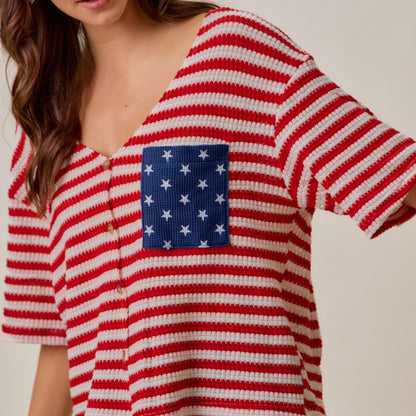 Layered view of the red, ivory, and blue stripe cardigan top with star pattern.