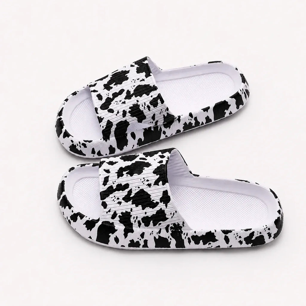 Women's white cow print EVA comfort slides featuring a lightweight slip-on design for all-day comfort.