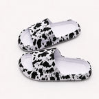 Women's white cow print EVA comfort slides featuring a lightweight slip-on design for all-day comfort.