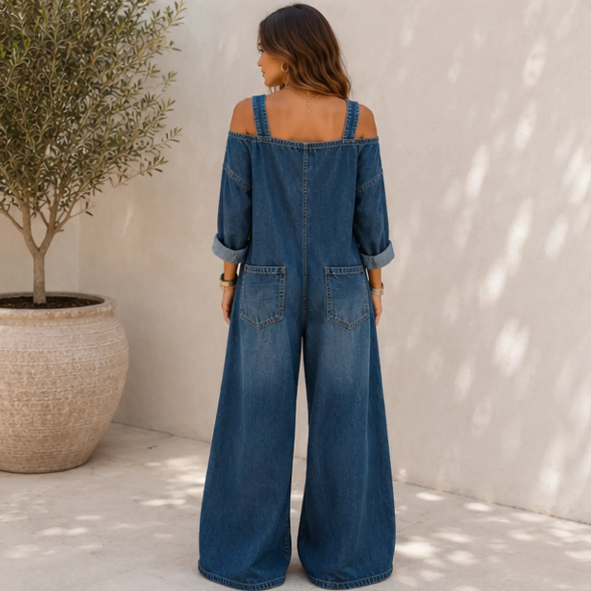 Back view of the Solazura Classic Wide Leg Denim Jumpsuit in navy blue showcasing adjustable straps, relaxed fit, rear patch pockets, and wide-leg denim design.