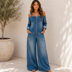 Woman wearing the Solazura Classic Wide Leg Denim Jumpsuit in blue with adjustable buckle straps, button-front detail, oversized pockets, and a relaxed wide-leg fit.