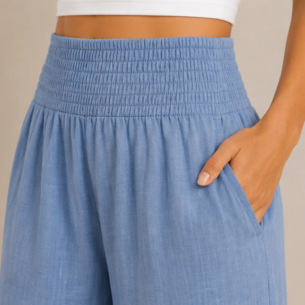 Close-up of stone blue lightweight high-waisted wide-leg lounge pants highlighting the smocked waistband, breathable fabric, and side pocket.